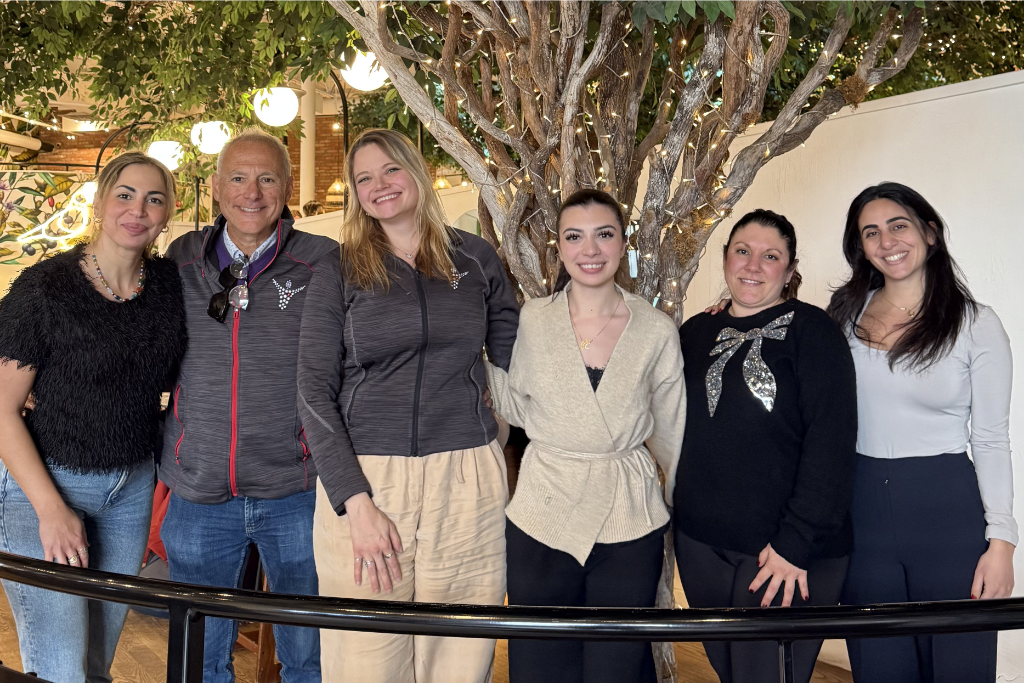 The six members of the LDSFC Team posing for a group portrait at a conference event, standing in front of a decorative lit tree.